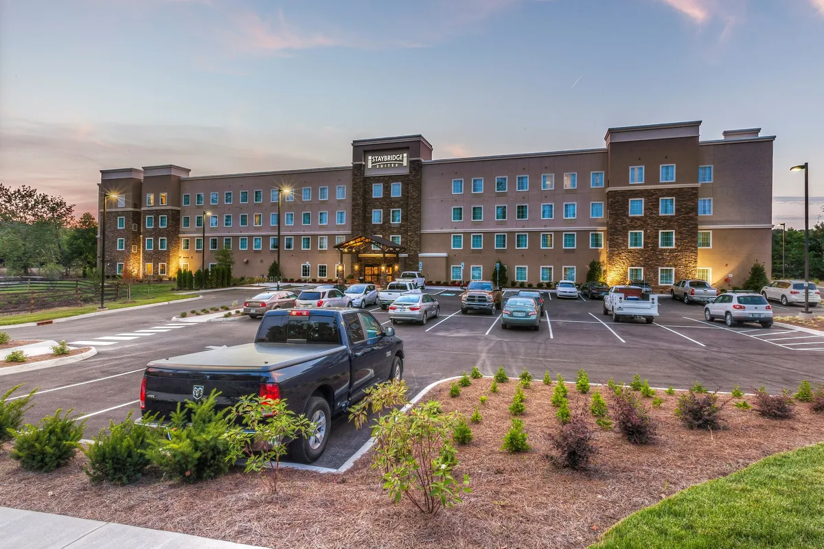 This image features the hotel's main facade and entrance, framed by landscaped greenery and an inviting canopy. The setting feels welcoming and lively, suggesting easy arrivals and departures for guests experiencing the local shopping and dining scene.