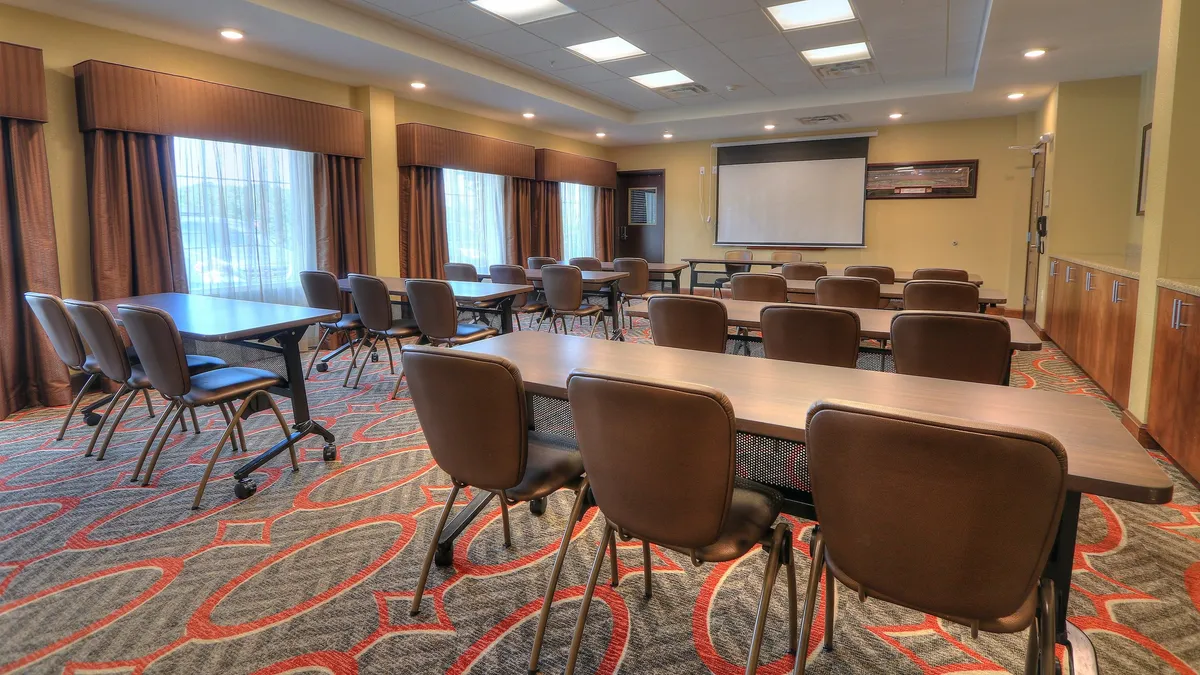 A large, sunlit interior space featuring rows of chairs, spacious tables, and expansive windows that allow natural light to pour in. Though primarily a meeting or seminar room, the design and bright ambiance subtly suggest opportunities for group gatherings and planning excursions into Knoxville or the nearby national parks.